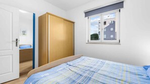 A bedroom with a bed, a wardrobe, a window, and a door. - Holiday apartment with air conditioning (Novigrad)