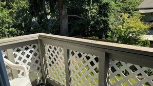 A wooden deck with a lattice railing, a plastic chair, and a tree in the background. - Contemporary, marine 2bd/1ba Apartment in Kent (kent)