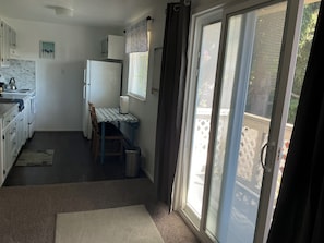 A compact kitchen with a dining table, a refrigerator, and a window with blinds.
