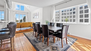 A dining area with a large table, black chairs, and a patterned rug.