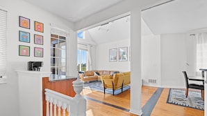 A spacious living area with a wooden floor, a yellow sofa, and a dining area with a table and chairs.