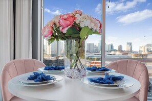 A dining table with pink chairs and a vase of flowers in the center.