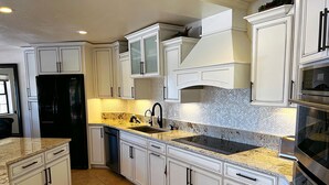 A kitchen with white cabinetry, a granite countertop, a black refrigerator, and a stainless steel oven. - THE BEST VIEW! On the Golf Course with Pool! (Lake Havasu City)