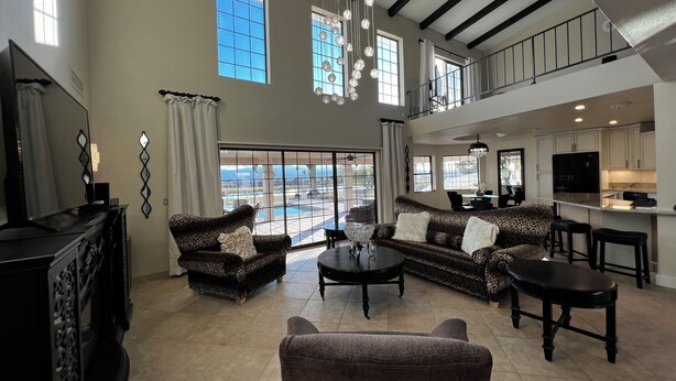 A spacious living room with a large sofa set, a coffee table, and a television. There is a balcony with a view of the ocean. - THE BEST VIEW! On the Golf Course with Pool! (Lake Havasu City)