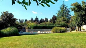 Une pelouse bien entretenue, avec une piscine, un petit bâtiment et une zone délimitée par une clôture.