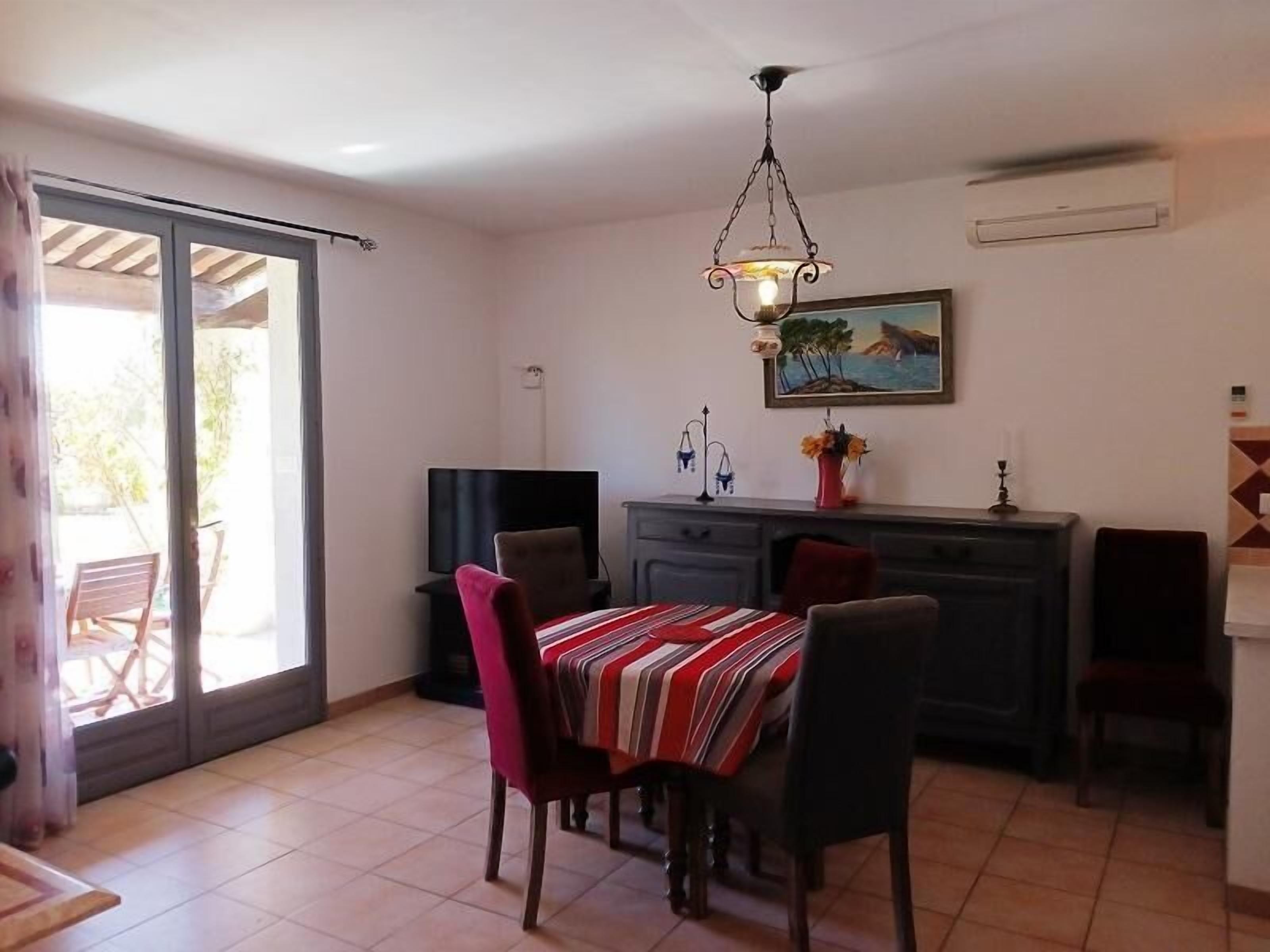 Un coin repas avec une table dressée pour quatre personnes, un téléviseur et un tableau accroché au mur.