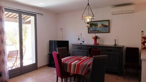 Un coin repas avec une table dressée pour quatre personnes, un téléviseur et un tableau accroché au mur.