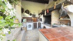 Eine rustikale Küche mit Steinböden, einer Waschmaschine und einem Backofen aus Ziegeln.