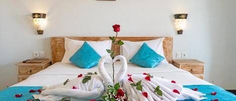 A neatly made bed with a blue bedspread, two pillows, and a decorative arrangement of towels and roses.