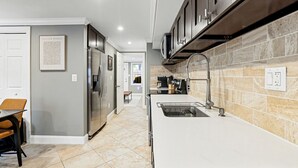 A modern kitchen with stainless steel appliances, a long countertop, and a tiled backsplash. - Historic Old Town Alexandria Home with modern luxury-3BR/3fullBA Walk to King St (Alexandria)
