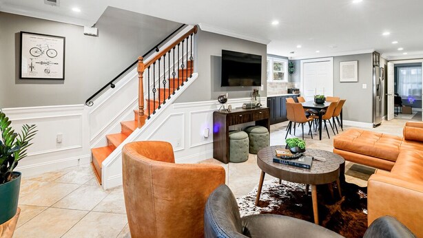 A modern living room with a staircase, leather sofas, a dining area, and a kitchen. - Historic Old Town Alexandria Home with modern luxury-3BR/3fullBA Walk to King St (Alexandria)