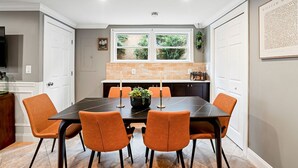 A dining area with a black table, six orange chairs, and a potted plant. - Historic Old Town Alexandria Home with modern luxury-3BR/3fullBA Walk to King St (Alexandria)