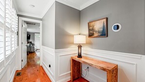 A hallway with wooden flooring, a white door, a console table with a lamp, and a painting on the wall. - Historic Old Town Alexandria Home with modern luxury-3BR/3fullBA Walk to King St (Alexandria)