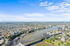 An aerial view of a cityscape with a prominent bridge spanning a river, surrounded by urban buildings and greenery. - Arabian Nights-Level 60-Meriton Suites (Brisbane)