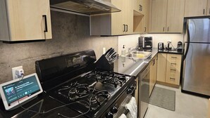 Een moderne keuken met roestvrijstalen apparatuur, houten kastjes en een digitaal apparaat op het aanrecht.
