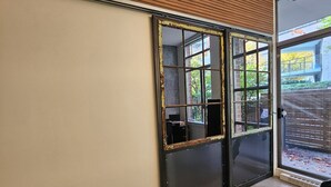 Een kamer met een schuifdeur naar een balkon, een grote spiegel en een kamerkleed met een structuur.