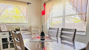 Ein Essbereich mit Tisch, Stühlen, einer Martini-Flasche und einer dekorativen Flamingofigur.