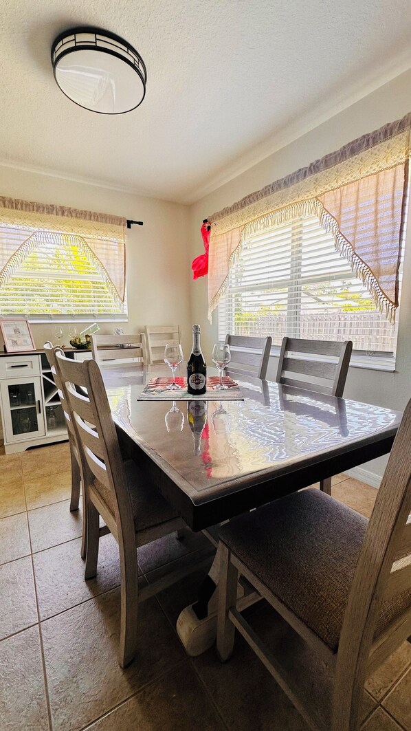 A dining area with a table, chairs, a bottle of Martini wine, and a decorative flamingo.