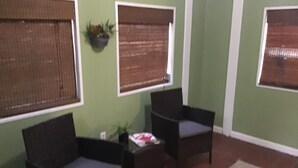 A room with two dark-colored sofas, a small table with a plant, and three windows with blinds. - Enjoyable house with AC in Augusta - 2 bedrooms, perfect getaway. (Augusta)
