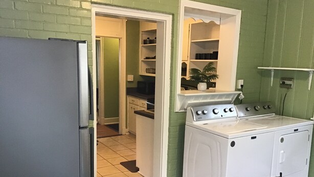 A compact kitchen with a refrigerator, stove, and washing machine. - Enjoyable house with AC in Augusta - 2 bedrooms, perfect getaway. (Augusta)
