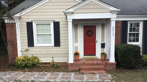 A single-story house with a red front door, white shutters, and a brick foundation. - Enjoyable house with AC in Augusta - 2 bedrooms, perfect getaway. (Augusta)