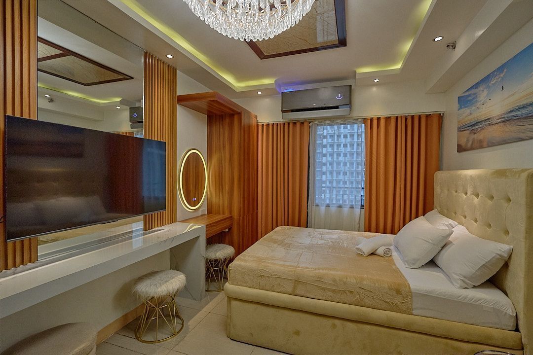 A modern bedroom with a large bed, a TV, and a chandelier.