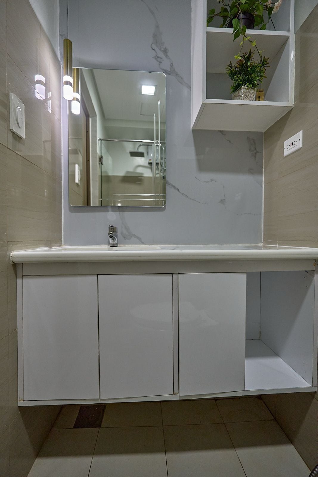 Casa de banho com toucador de mármore, espelho e prateleira com plantas.