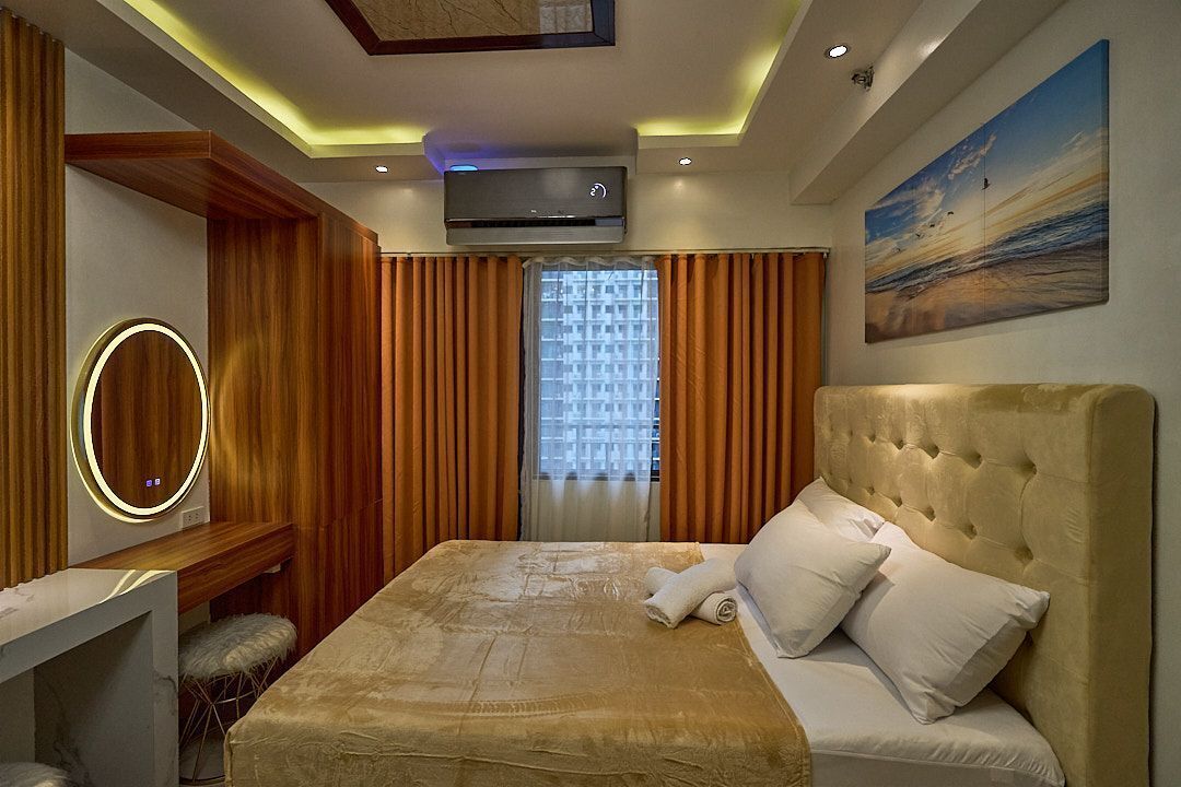 Una habitación de hotel moderna con una cama grande, un escritorio, una tocador con espejo y un aire acondicionado instalado en el techo.
