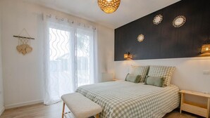 Een slaapkamer met een bed, een bankje, nachtkastjes en decoratieve wandkunst.