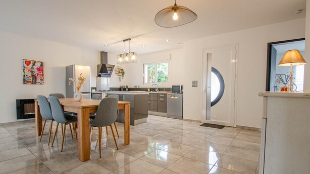 Een moderne keuken met een eethoek, met een groot schiereiland, roestvrijstalen apparatuur en een moderne hanglamp.