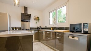 Een moderne keuken met roestvrijstalen apparatuur, een groot eiland en een raam dat voor natuurlijk licht zorgt.