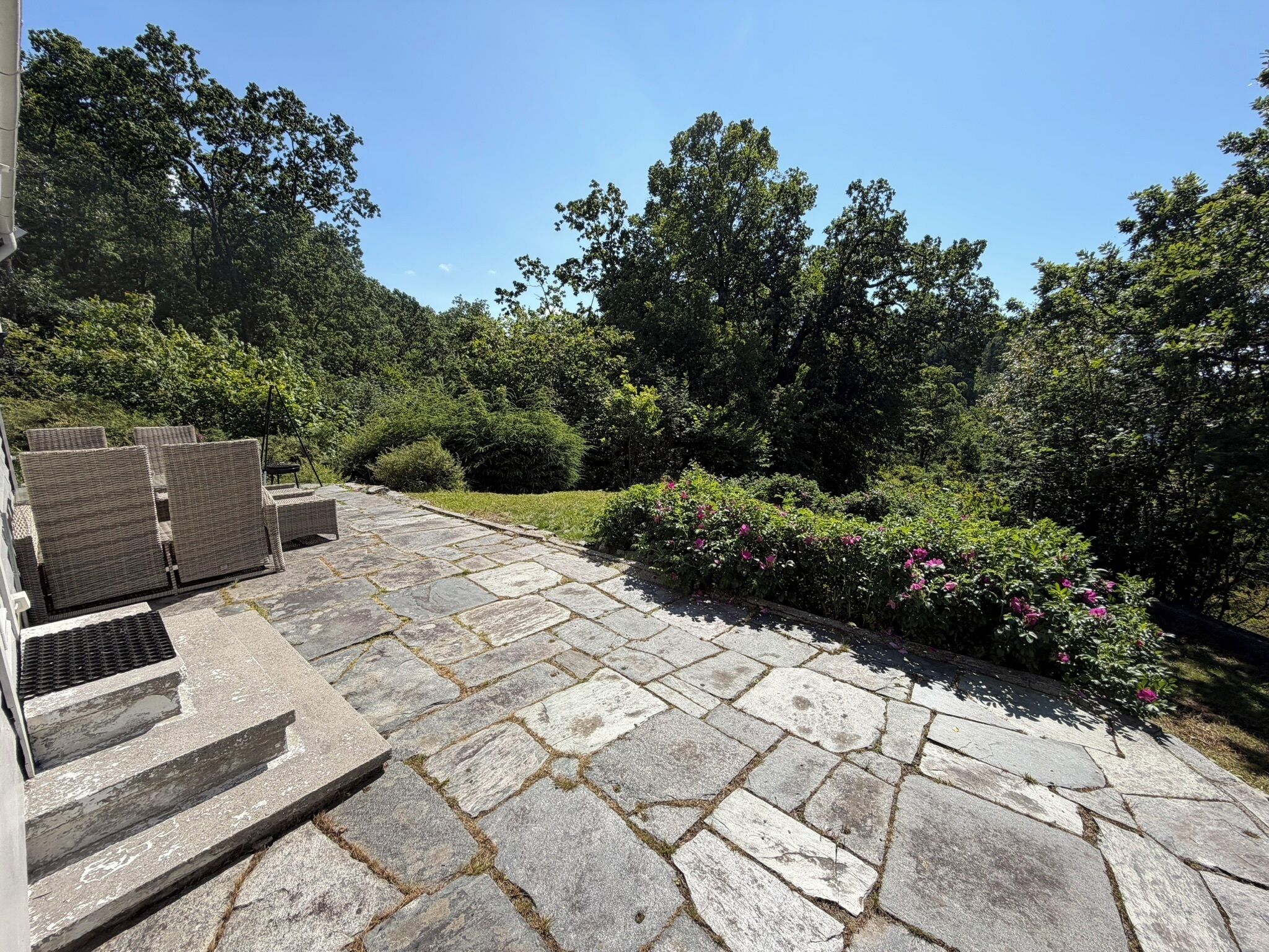 A stone patio with outdoor furniture and a garden area with shrubs and flowers.