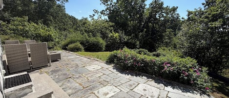 A stone patio with outdoor furniture and a garden area with shrubs and flowers.