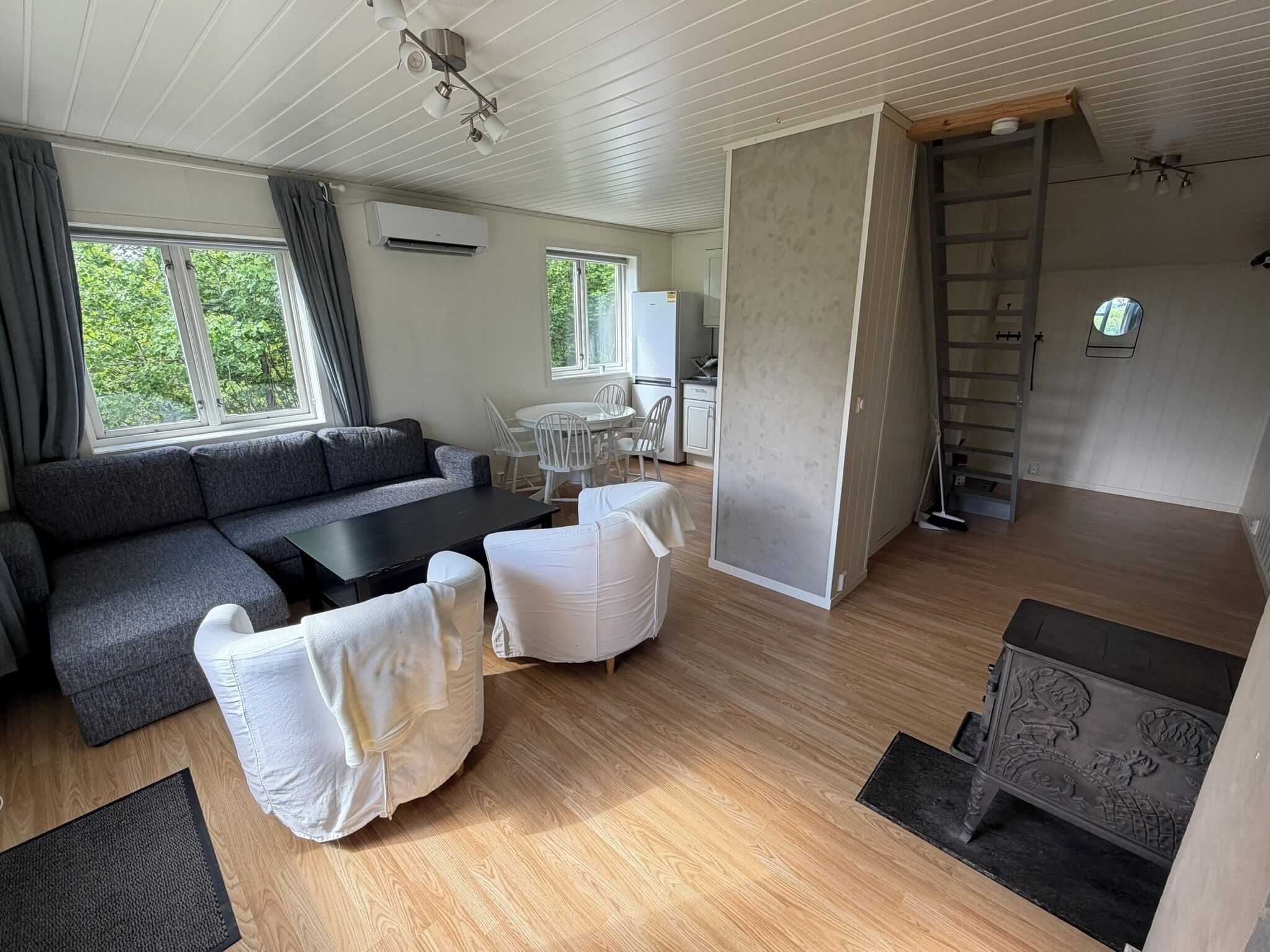 A modern living room with a sofa, chairs, a dining table, and a kitchen area.