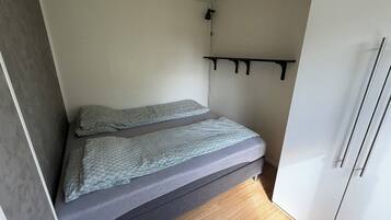 Een kleine kamer met een bed, een klein kastje en een kledingkast.
