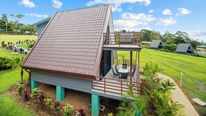 Een modern huis met een schuin dak, een balkon en een verzorgde tuin.