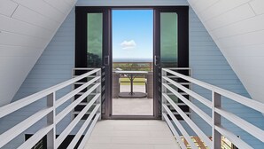 Een balkon met een tafel en stoelen, een helder uitzicht op de lucht en een leuning.