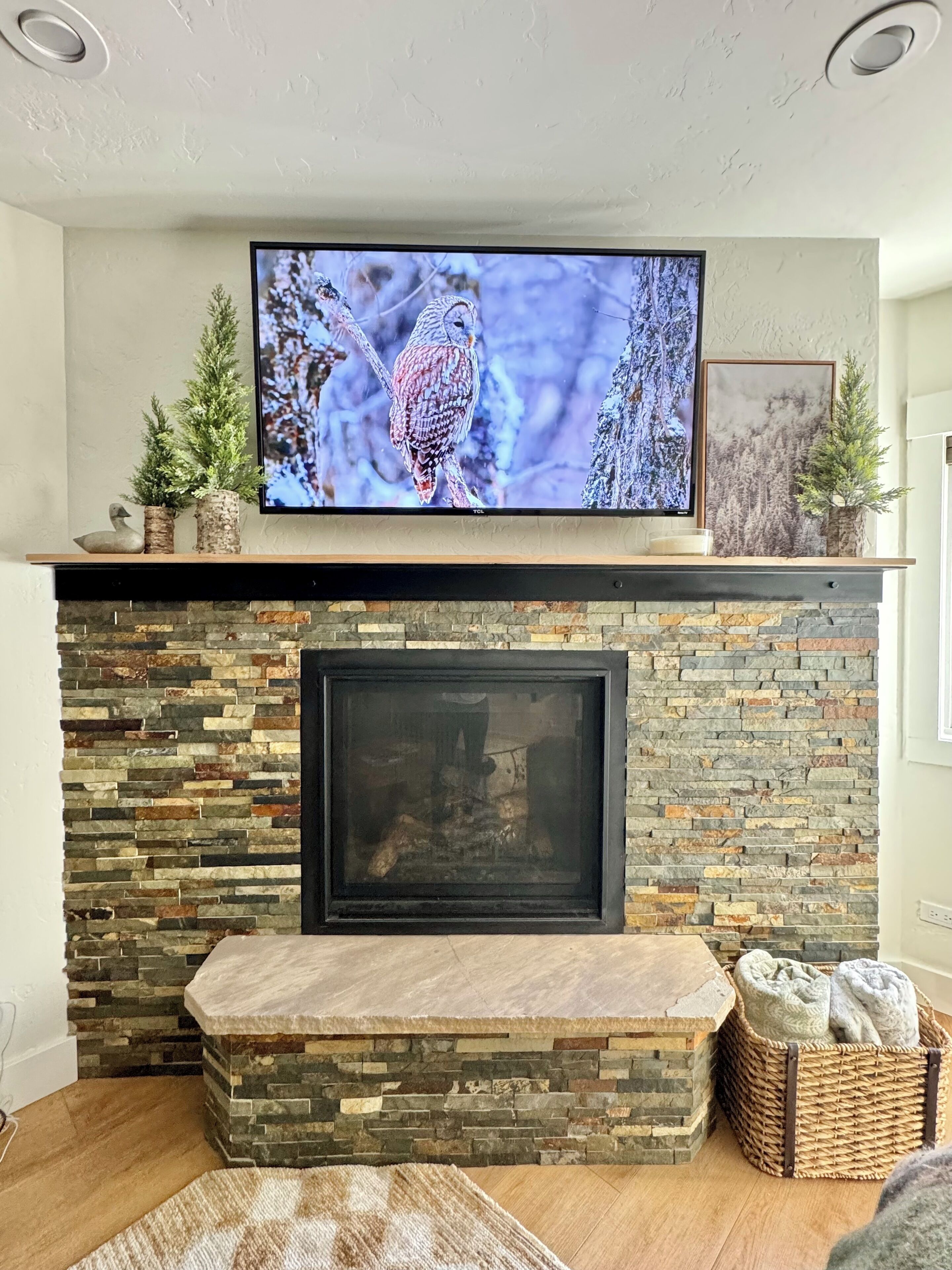A fireplace with a stone surround and a flat-screen TV mounted above it.