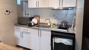 Une cuisine moderne avec des meubles blancs, un lave-vaisselle encastré, une cuisinière et une machine à café.