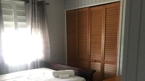 Een slaapkamer met een bed, een houten kledingkast en een klein tafeltje.