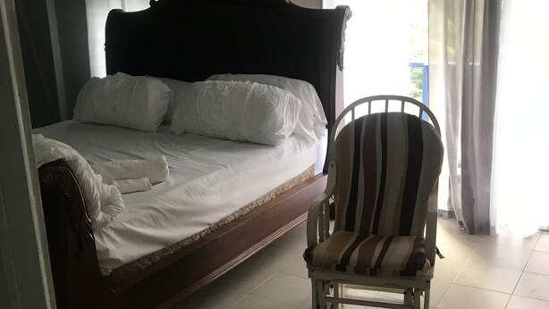 Een slaapkamer met een bed, een stoel en gordijnen.