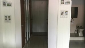 A room with a tiled floor, a door leading to a hallway, and a small bathroom with a toilet and sink. - Enjoyable 2nd story, 3-bedroom house with AC in Coamo, PR (Coamo)