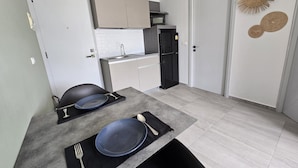 A compact kitchen with white cabinets, a black refrigerator, and a dining area with a table set for two. - Modern Retreat 1- Bed T3-529 (Chalong)