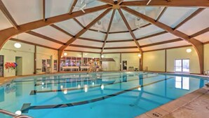An indoor swimming pool with a high ceiling and wooden beams.