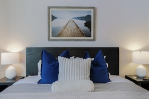 A hotel room with a bed, two nightstands, a headboard, and a framed picture of a pier.