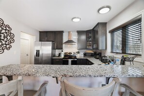 A modern kitchen with granite countertops, stainless steel appliances, and dark cabinetry.