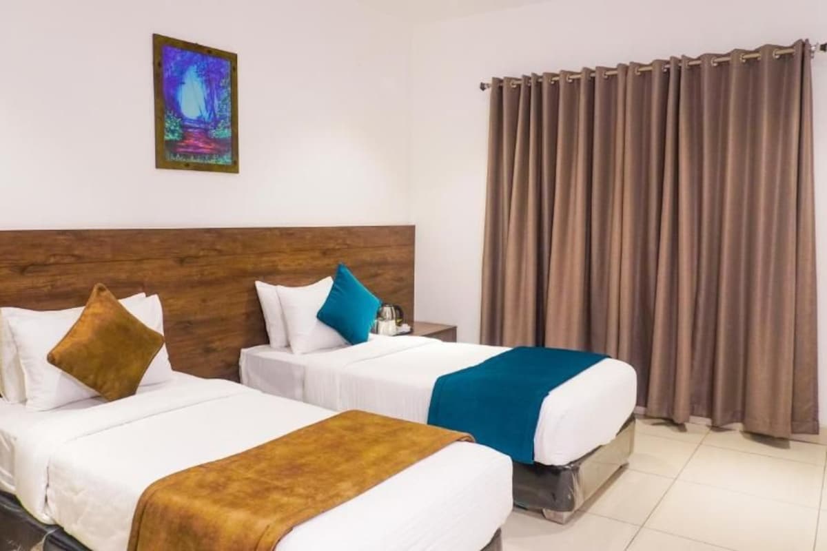 Ein Hotelzimmer mit zwei Betten, einem hölzernen Kopfteil, einem Gemälde an der Wand und einem Vorhang.