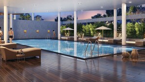 Une piscine intérieure moderne, dotée de chaises longues, de parasols et d’une terrasse en bois.