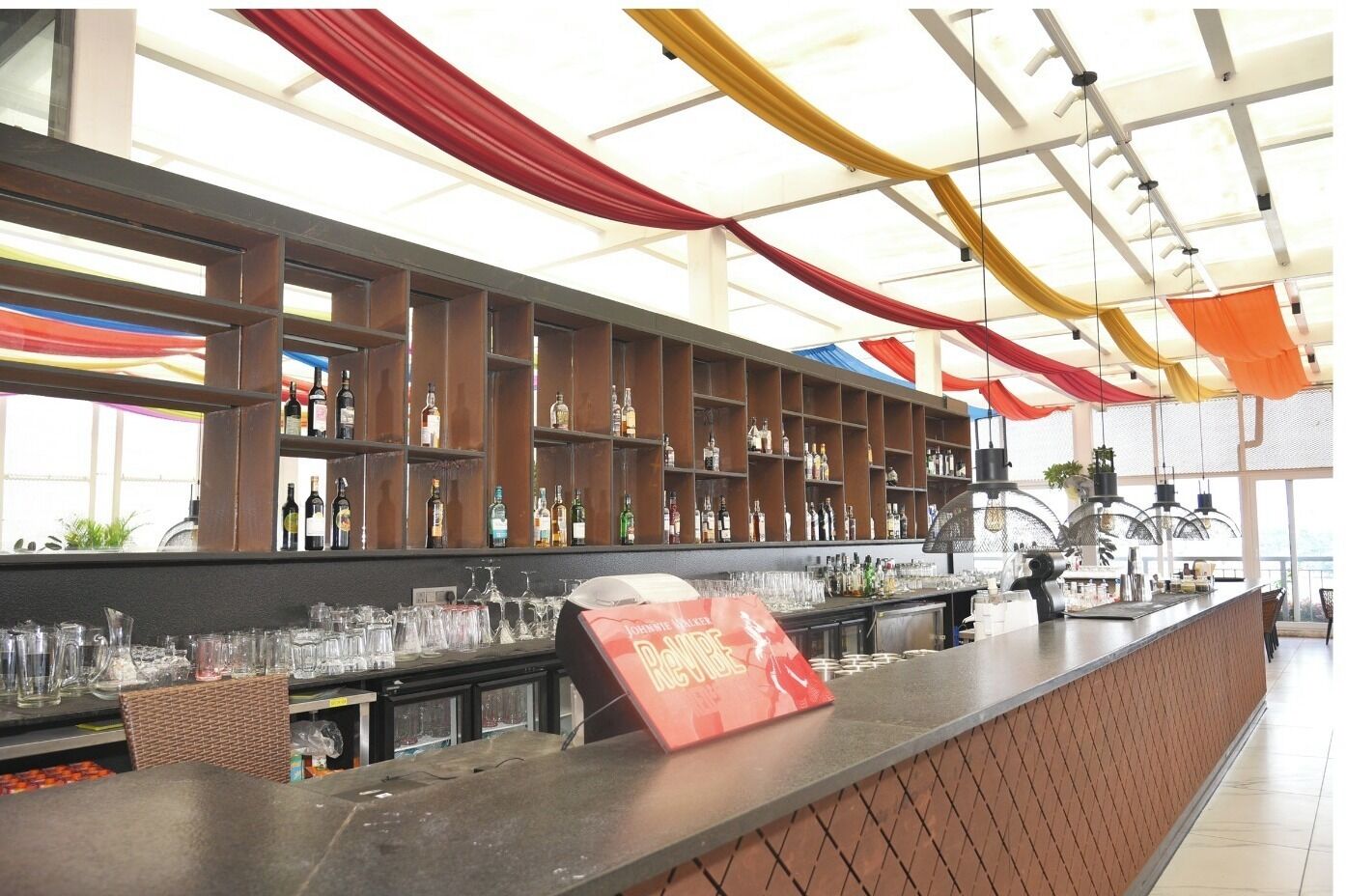 A bar area with shelves stocked with bottles, glasses, and a sign indicating a special offer.
