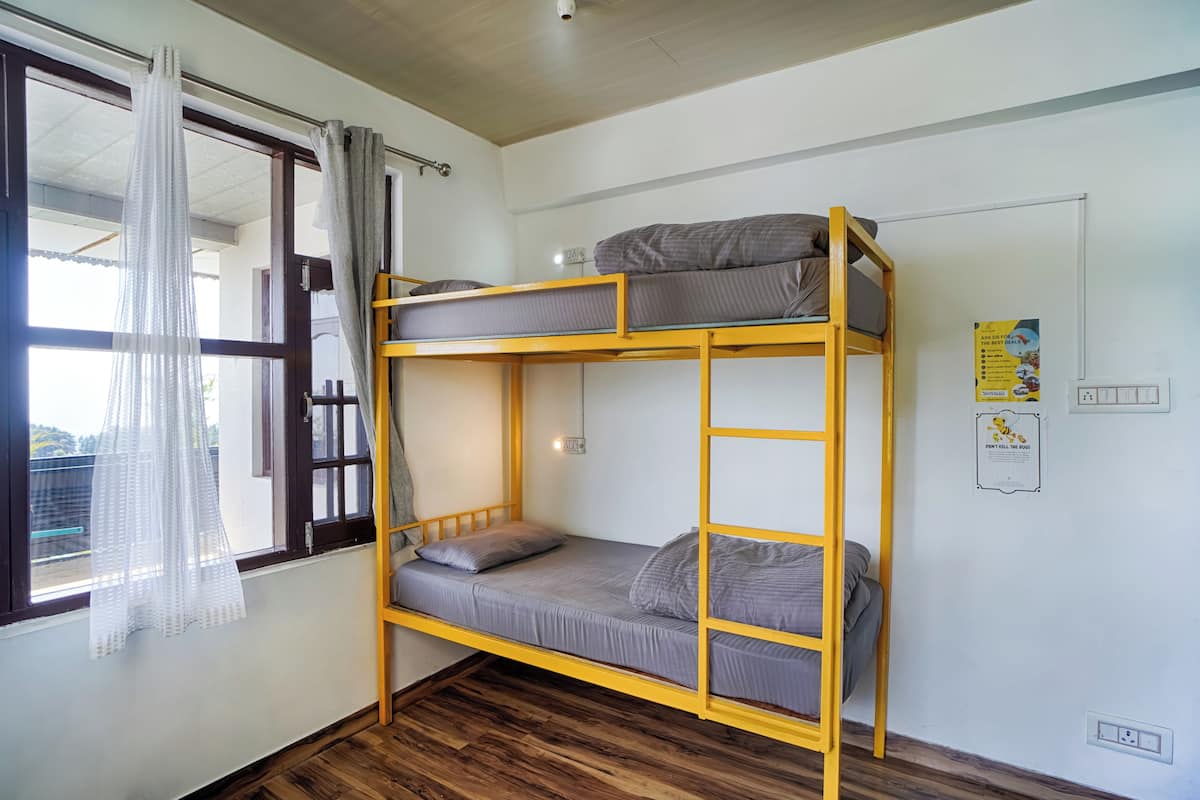 A bunk bed room with a window, curtains, and a poster on the wall.